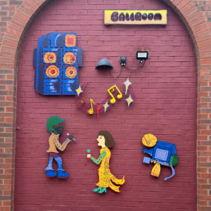 An artwork depicting two singers and musical apparel on a red wall
