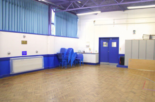 An empty room with wooden floorboards, blue double doors, blue curtains and large grey cupboards in the background next to the doors.