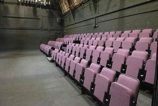 Pink cinema style seating in an empty room with grey walls