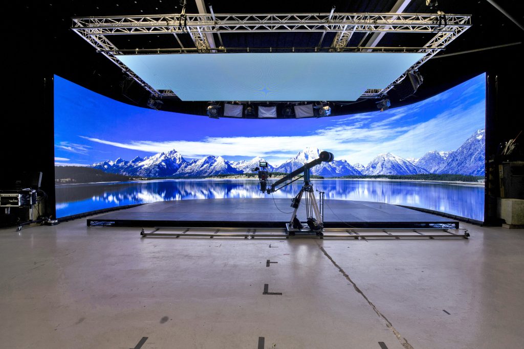 The interior of a film studio with a panoramic background, a stage and a camera set