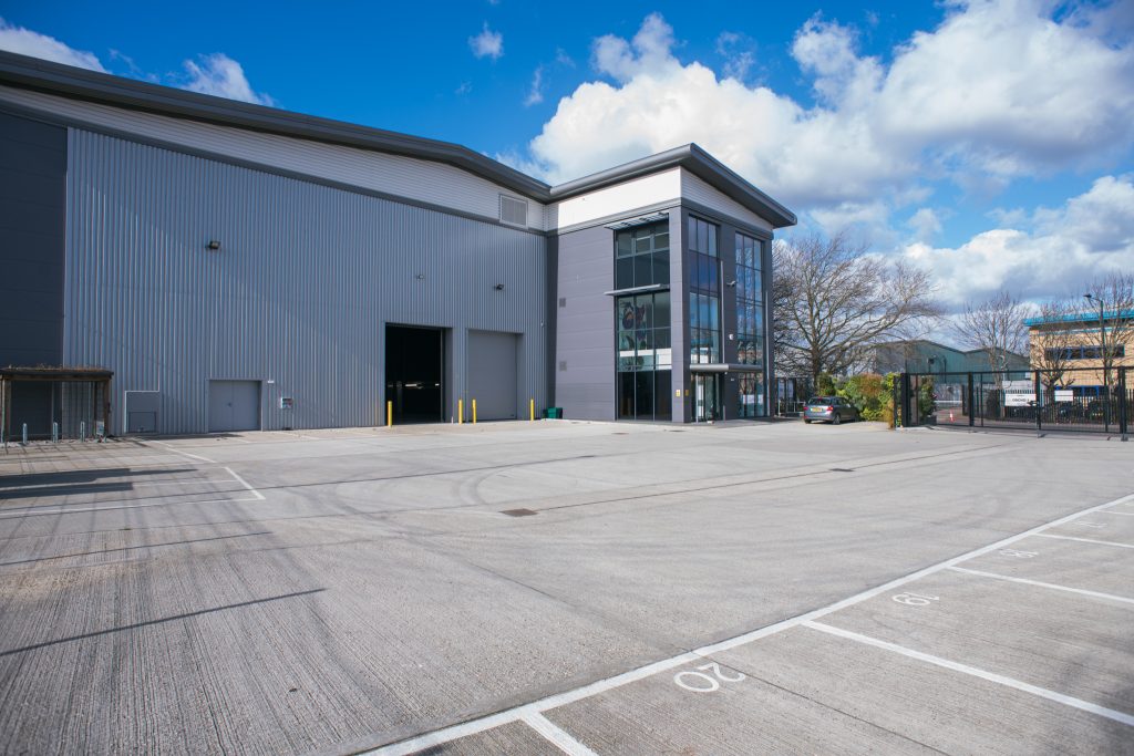 The exterior of a modern film studio on a sunny day sat within a carpark