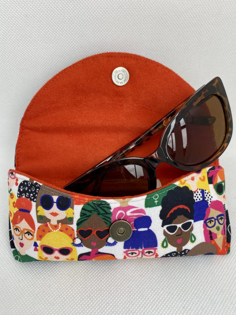 sunglasses tucked into the rim of an orange beanie hat