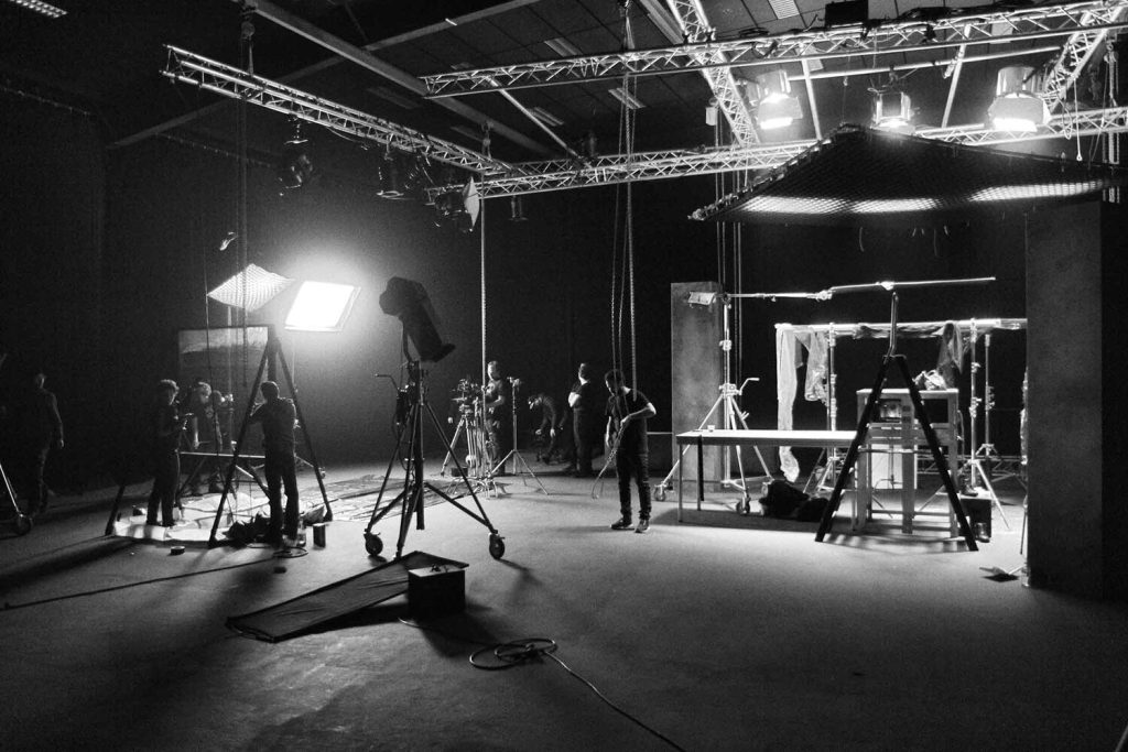 A black and white photo of a film or theatre studio with a few crew working on