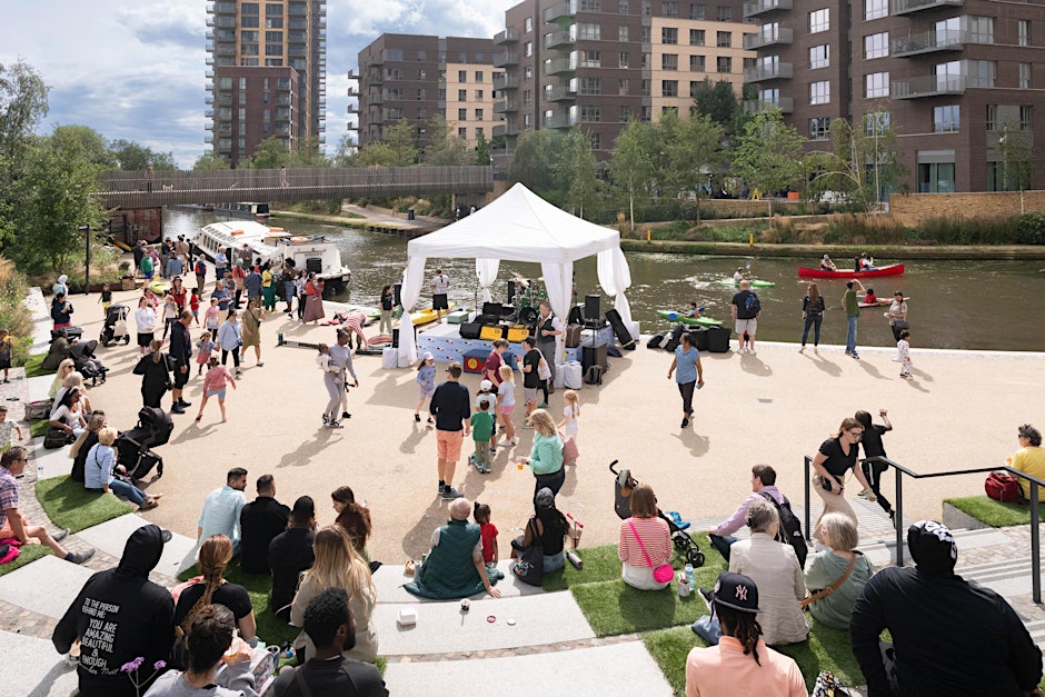 A sunny day at Greenford Quay and people are gathered around a stall as part of a canal festival