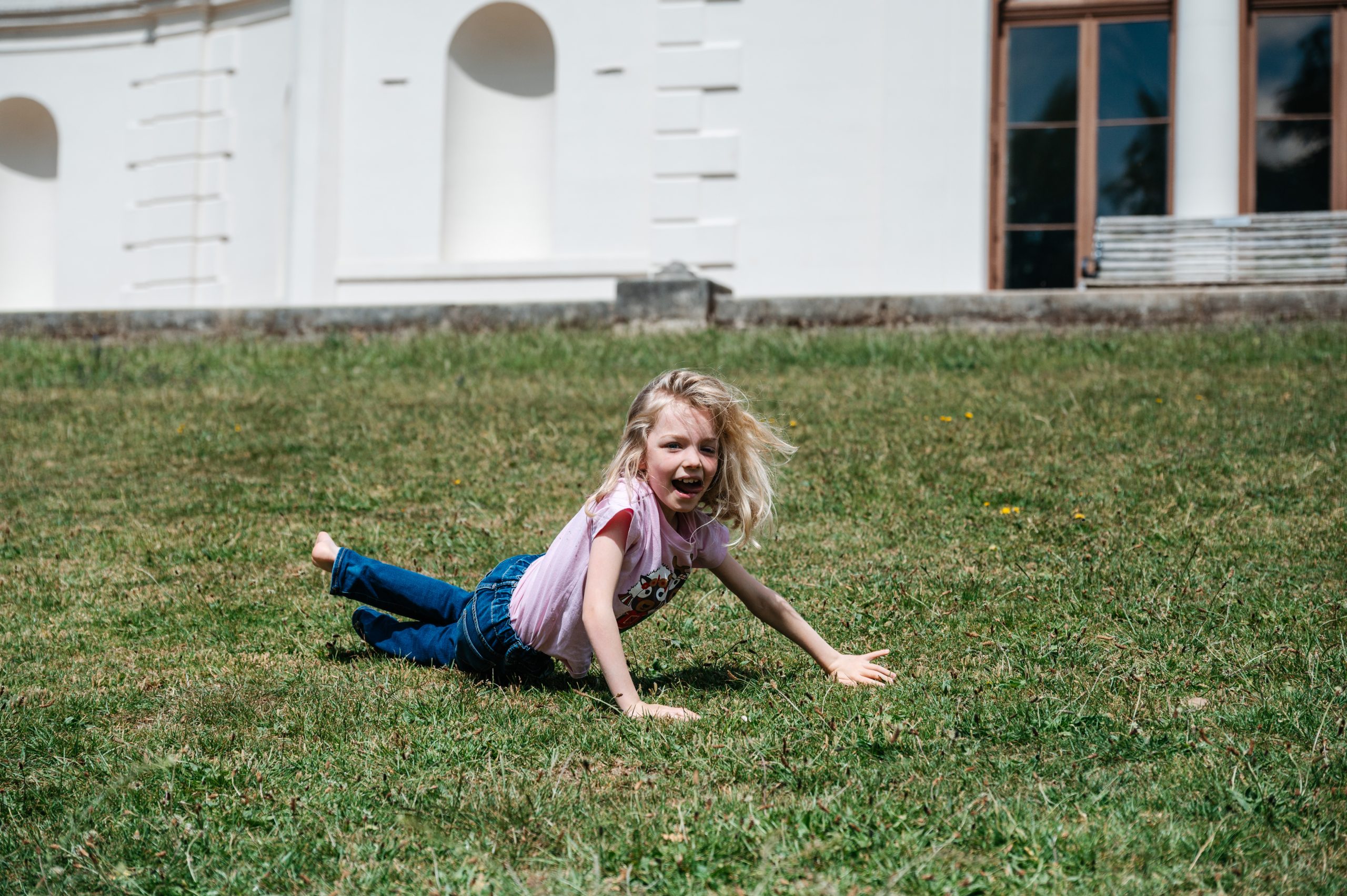 A girl with long blond hair lies in the grass in the grounds of Gunnersbury Park