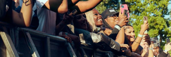 People in an audience smiling and filming with their phones