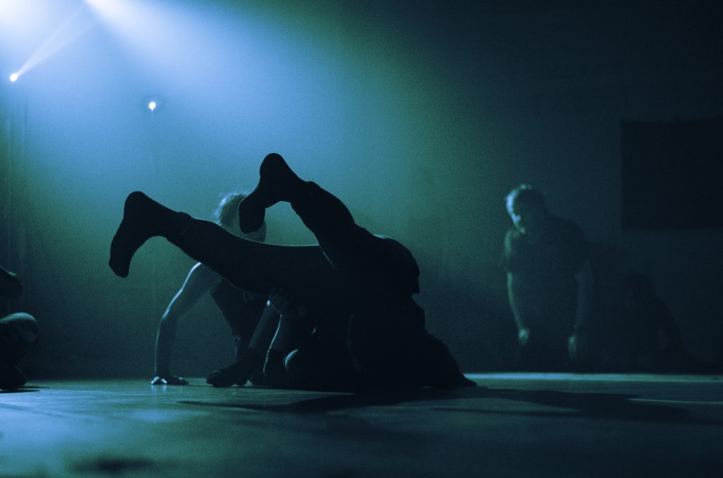 People dancing, they are silhouetted in black against a blue background