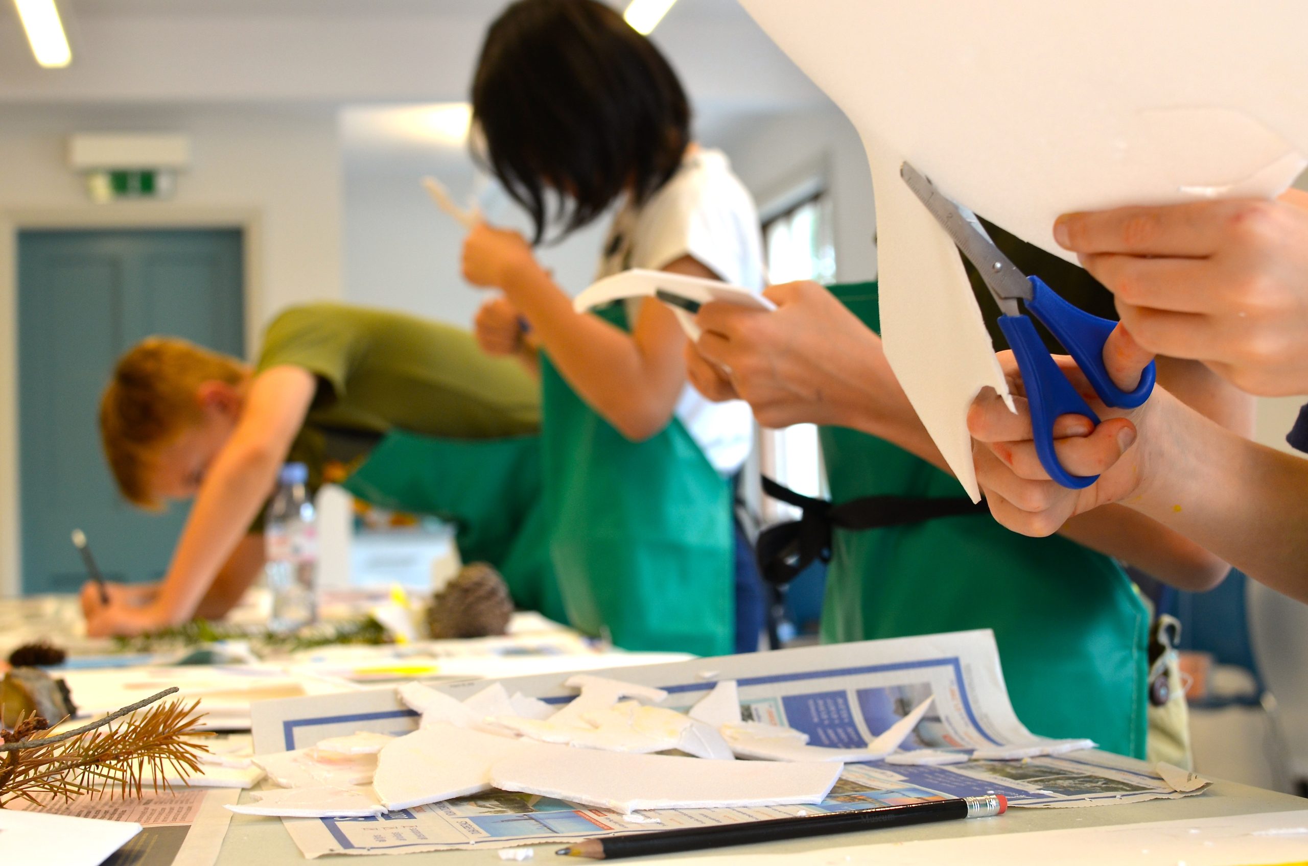 Four young people in green aprons stood in a row doing crafts