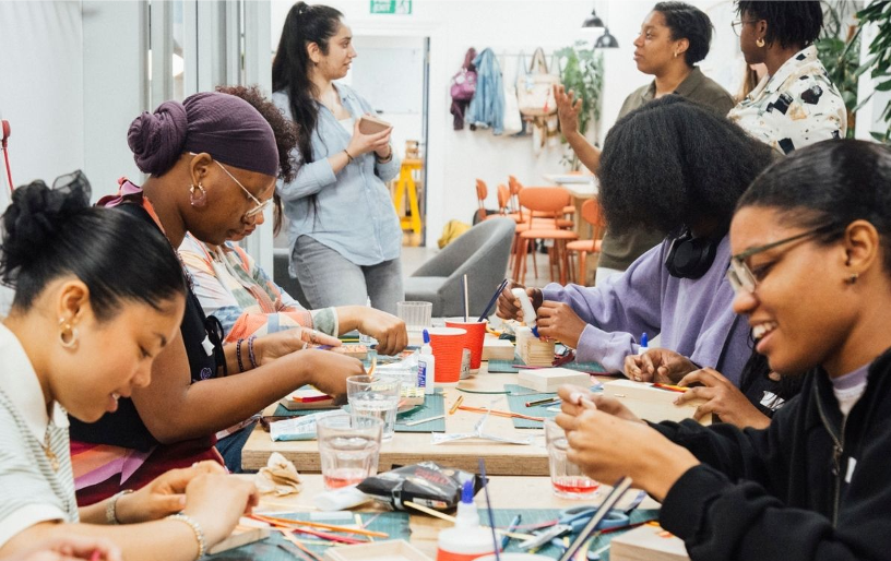 Several people in a bright room sat at a table doing craft activities
